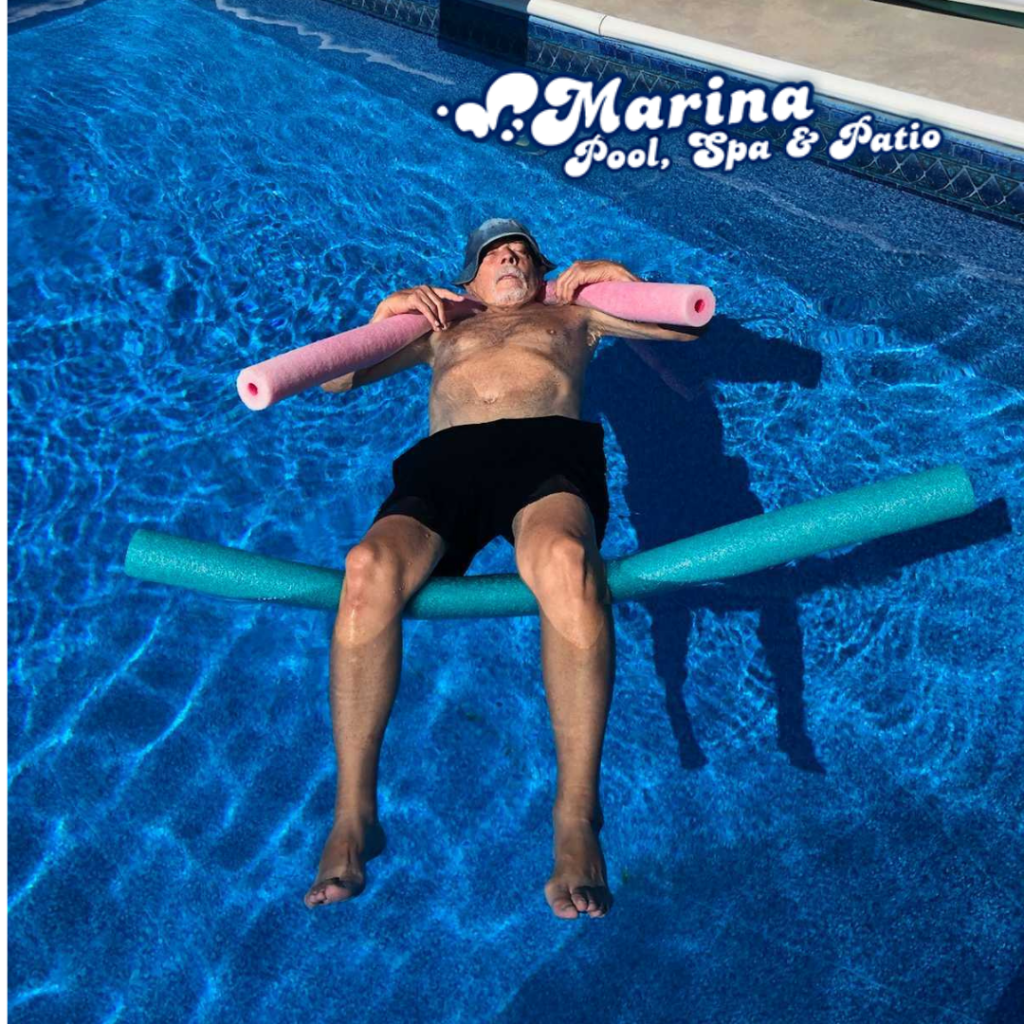 A man floats in a pool with foam noodles at a Marina Pool Spa & Patio customer's backyard, showcasing the relaxation that comes with shopping at 10777 West 6th Avenue, Lakewood, CO